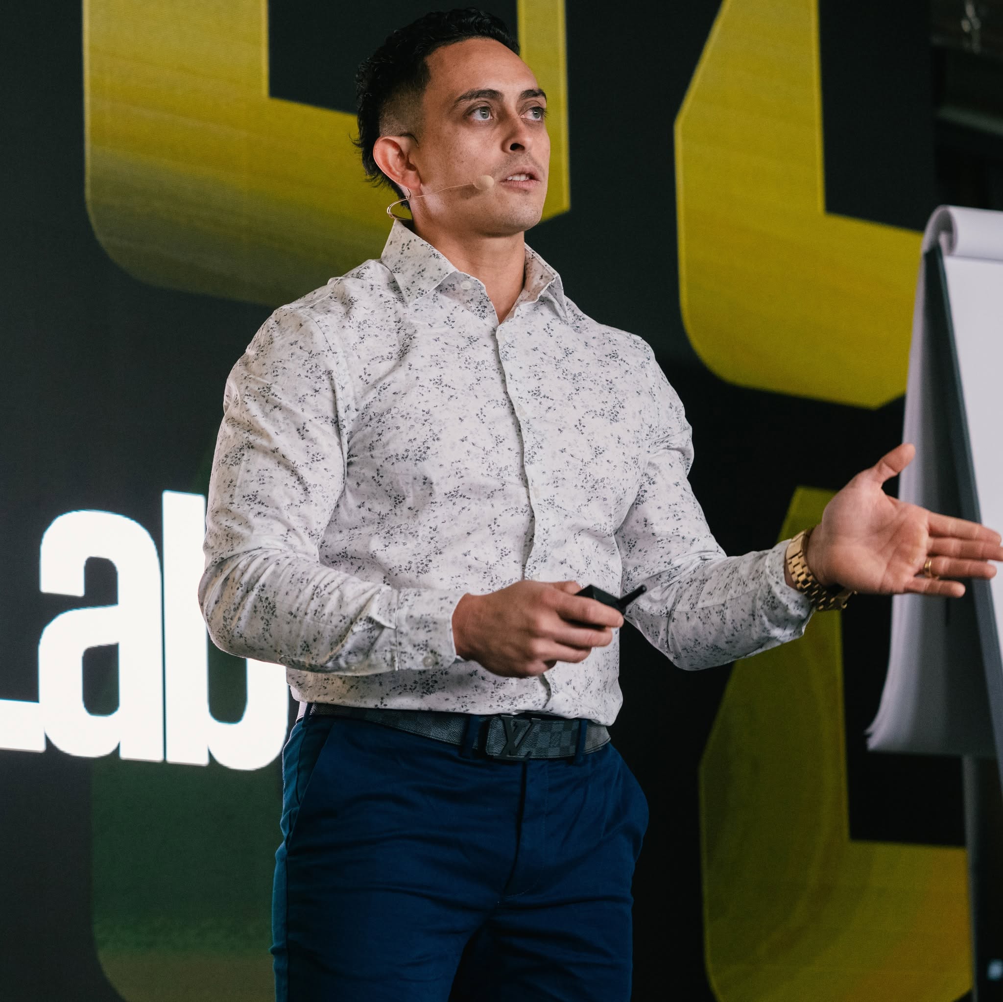 Jonathan Montoya speaking on stage in his patterned white shirt